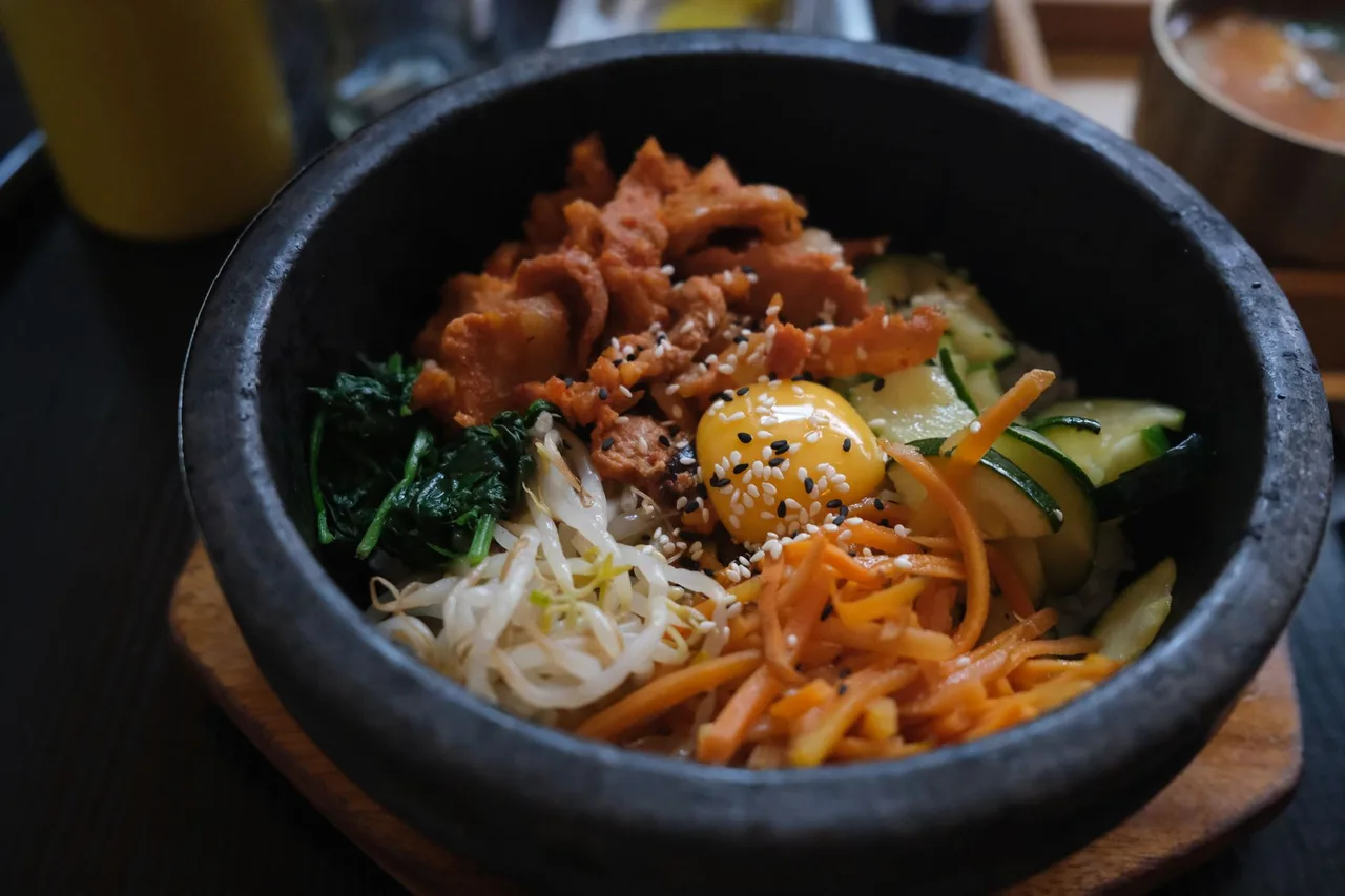 A stone bowl of bibimbap piled with seasoned vegetables and rice